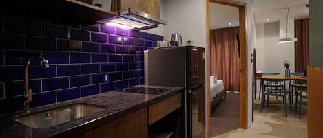 Una cocina moderna con azulejos azul oscuro, un refrigerador de acero inoxidable y un horno empotrado.