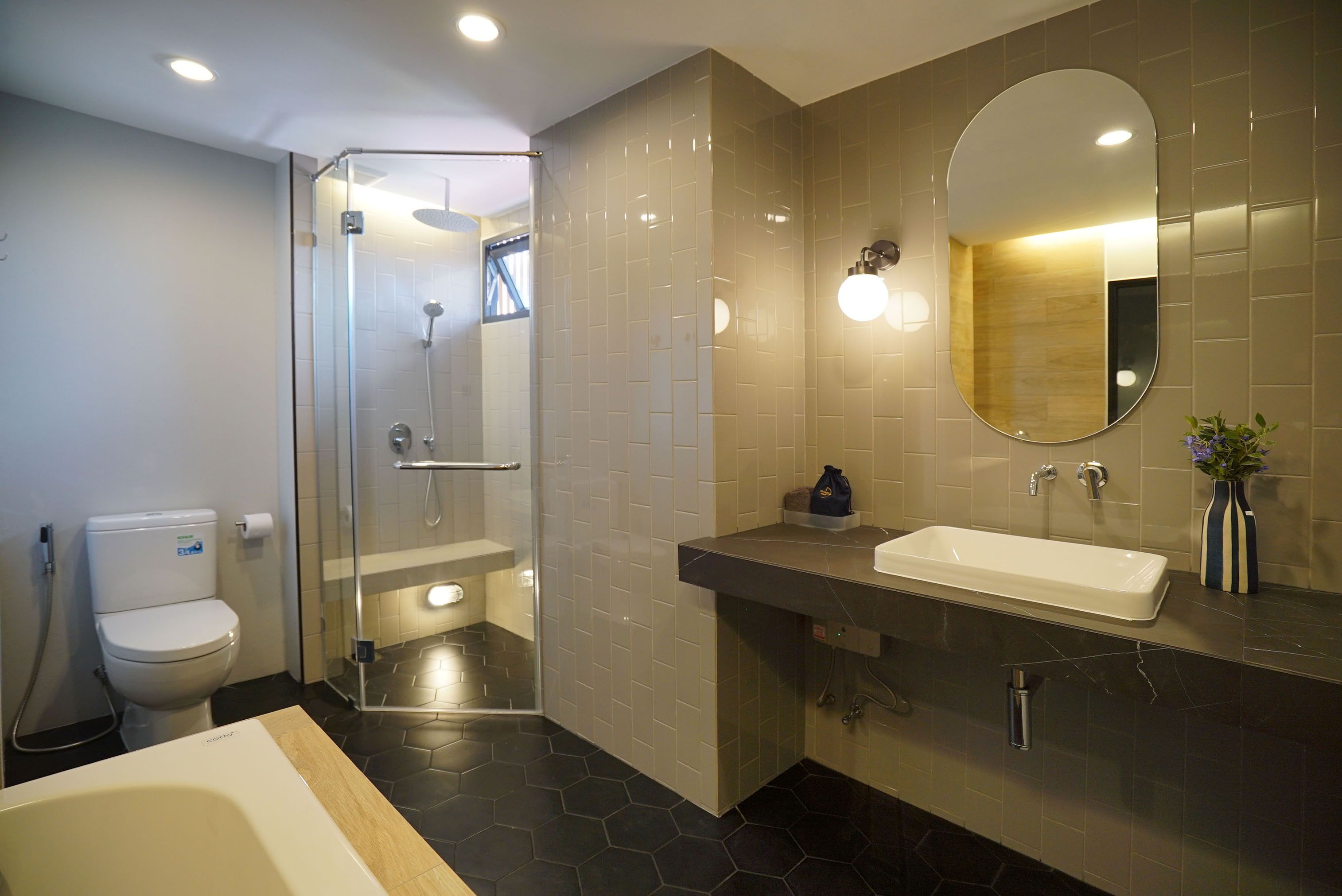 A modern bathroom with a glass-enclosed shower, a white toilet, a large sink, and a mirror.