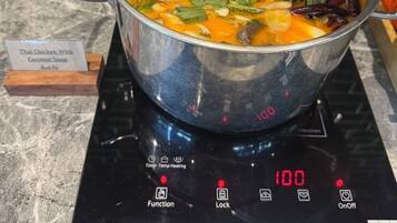Ein Topf thailändisches Hühner-Kokosnuss-Suppe auf einer digitalen Induktionskochplatte, eingestellt auf 100 Grad Celsius.