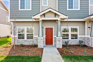 A two-story residential building with a stone facade, a red front door, and a number '1267' on the wall. - Upscale Townhome | Near The Village & Boise Mall-67 (Boise)