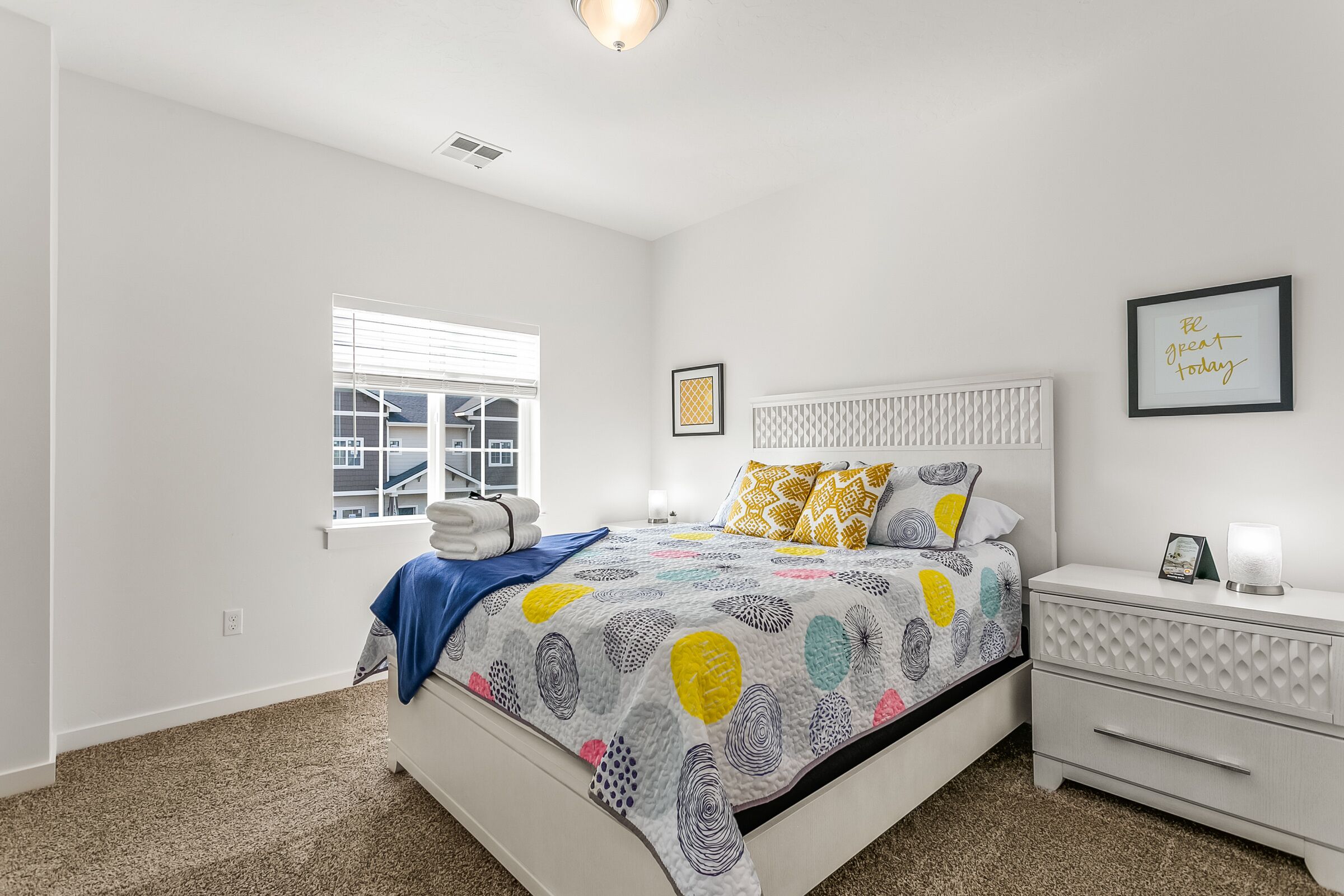 A bedroom with a bed, bedside table, and a window.