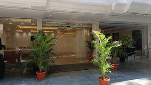 Ein Hotel Eingang mit Glastür, Pflanzkübeln und einem Blick auf die Rezeption.