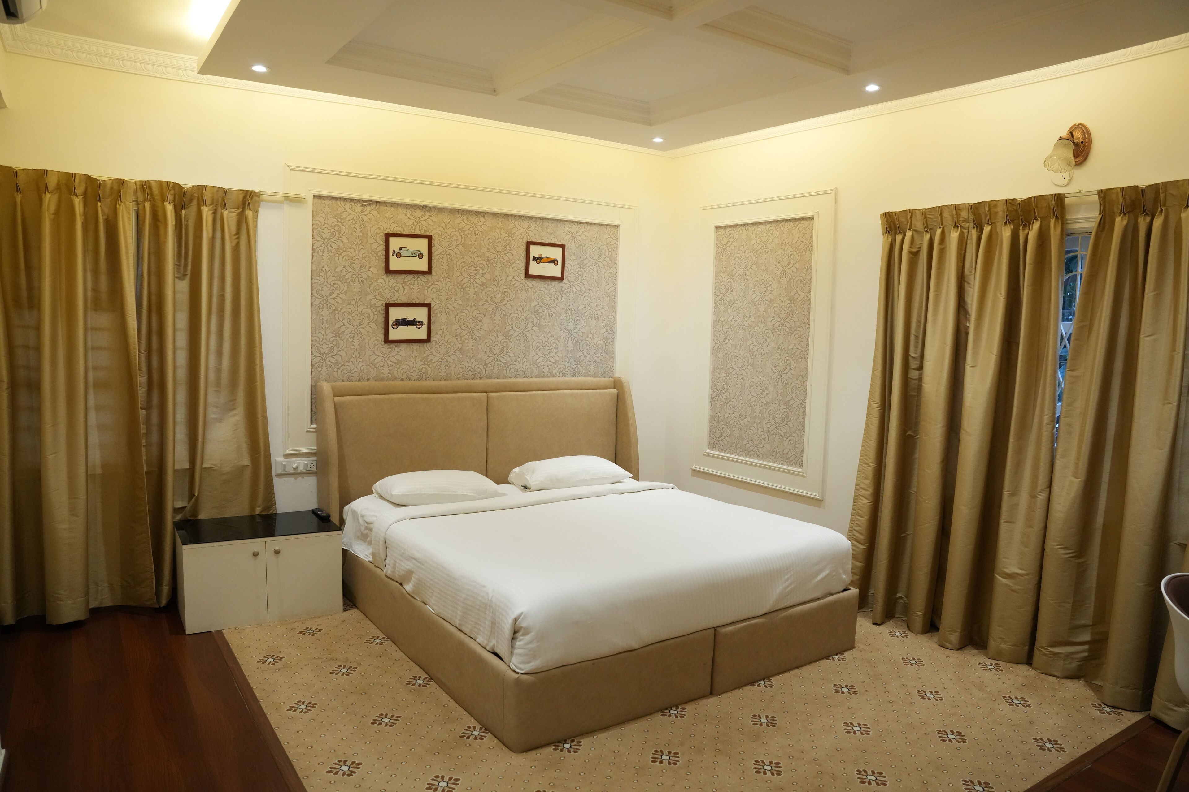 A bedroom with a large bed, a nightstand, a wardrobe, and a window with curtains.
