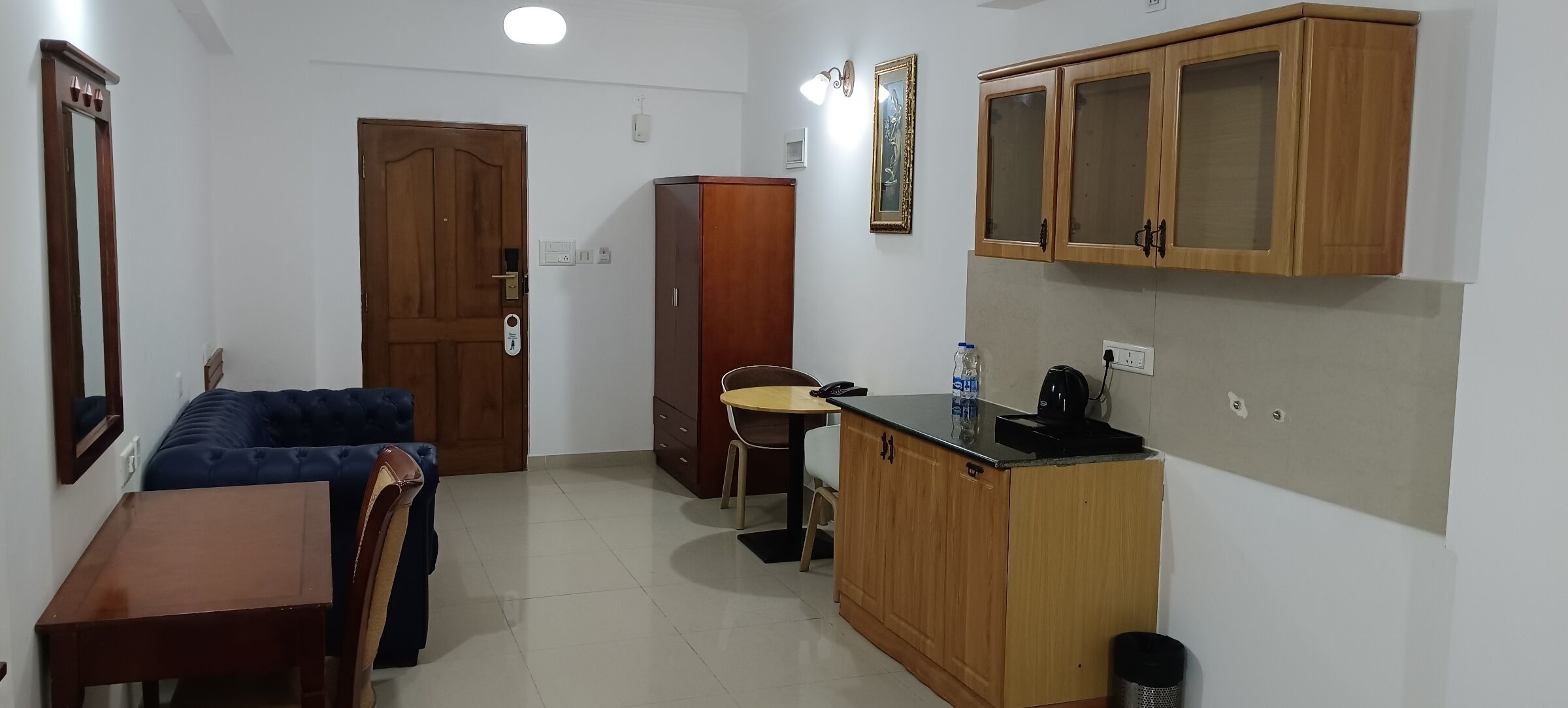 A compact living space with a kitchenette, a dining area, a wardrobe, and a door.