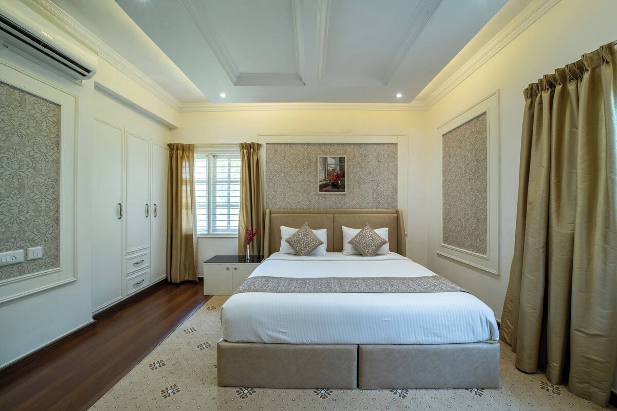 Un dormitorio amplio con una cama grande, un armario y una ventana con cortinas.