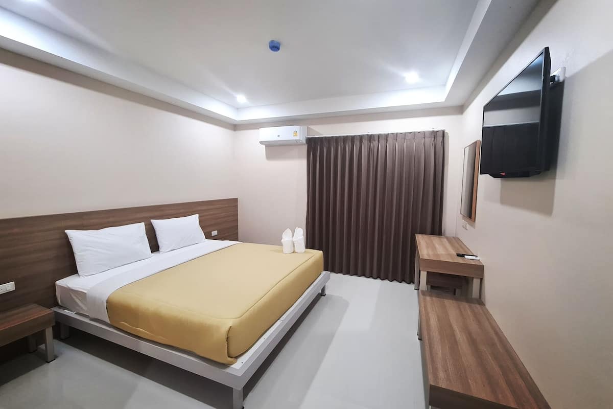Habitación de hotel con cama, mesita de noche, televisor y aire acondicionado.