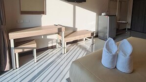 Ein Hotelzimmer mit einem Bett, einem Schreibtisch, einem Stuhl, einem an der Wand befestigten Fernseher und einem Kühlschrank.