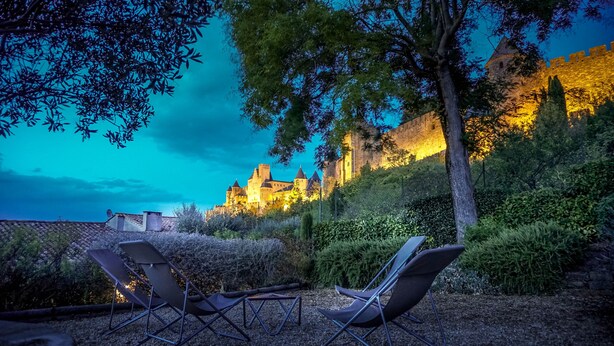 Ein Innenhof mit Außenbestuhlung und einer Burg im Hintergrund.