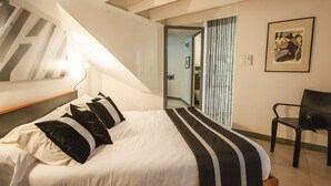 Ein modernes Hotelzimmer mit einem Bett, einem Sessel und einem gerahmten Kunstwerk an der Wand.