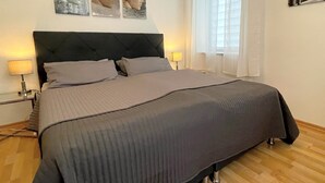 Una cama bien hecha con un cabecero oscuro y dos lámparas de noche.
