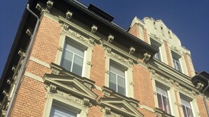 Un edificio de varios pisos con detalles arquitectónicos ornamentados, incluyendo molduras decorativas y estatuas.