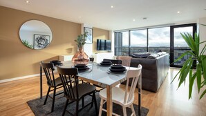 A modern dining area with a round mirror, a vase, and a table set for four. - Riverview Apartments (Glasgow)