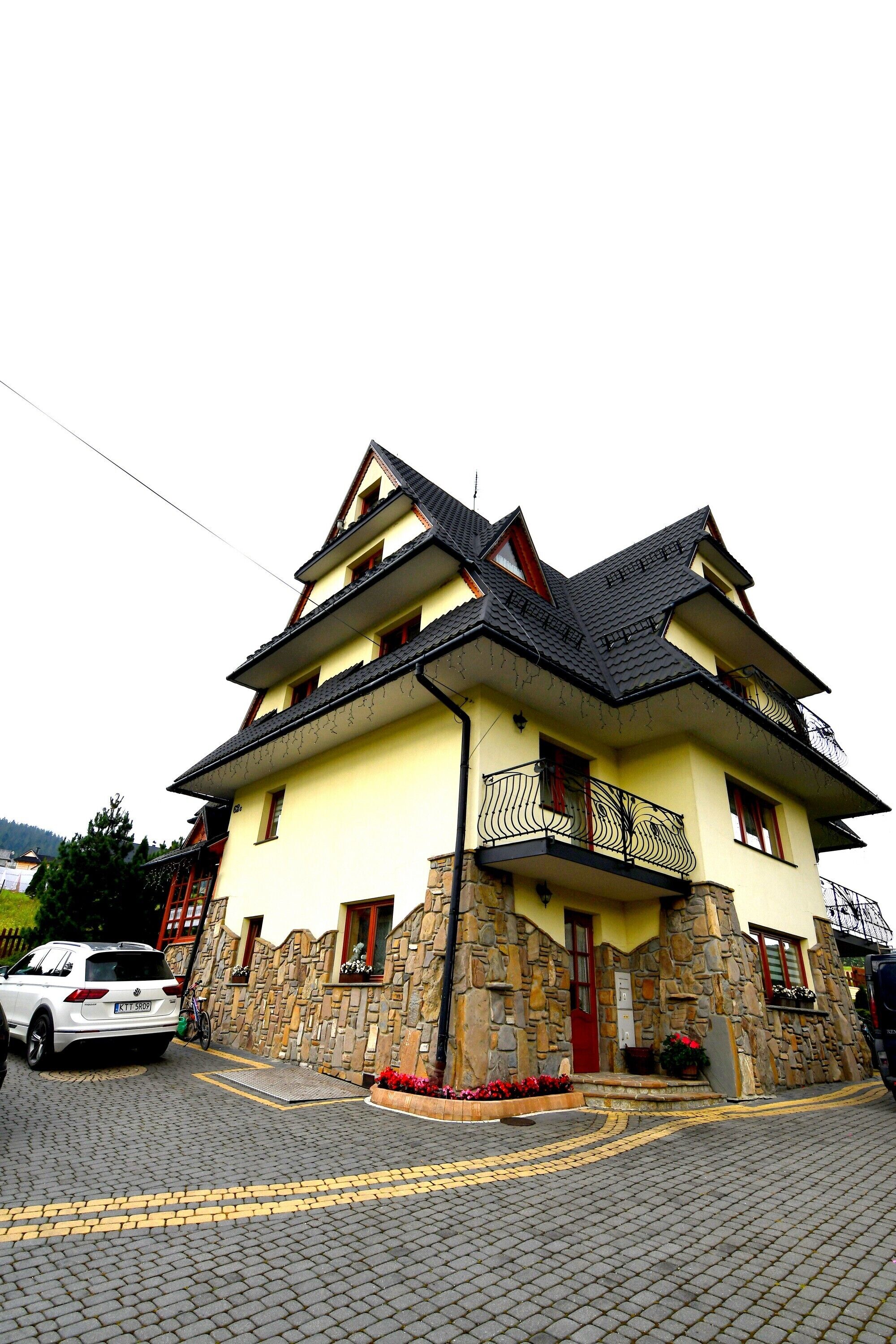 A two-story building with a stone facade, a red door, and a balcony.