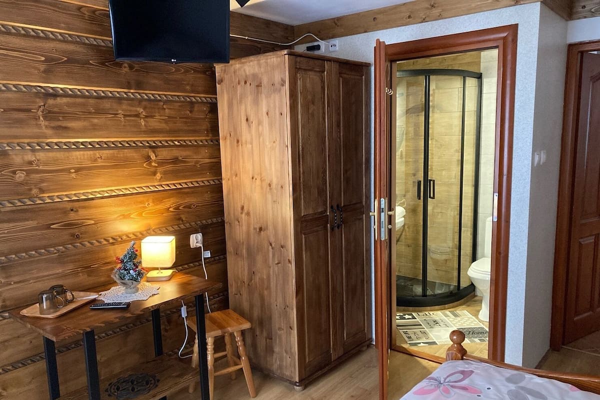 A wooden room with a desk, chair, and wardrobe.