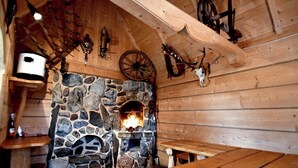 A rustic stone fireplace with a fire, wooden benches, and a stone wall. - Willa Dziubas (Poronin)