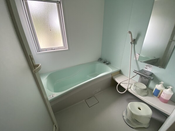A bathroom with a bathtub, a toilet, a sink, a mirror, and a window. - Green Hills New Minami (Yamanakako)