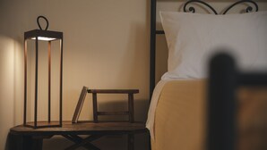 A bed with a white pillow, a bedside table with a lamp, and a small wooden stool. - Conte Orsini Apartment (Conversano)