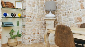 A dining area with a stone wall, a table with chairs, a lamp, and a cactus plant. - Conte Orsini Apartment (Conversano)