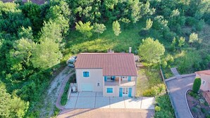 A two-story house with a red-tiled roof, surrounded by lush greenery. - La Rosepierre, studio with a breathtaking view of the red-blue-green Salagou mountains (Liausson)
