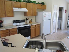 A kitchen with wooden cabinets, a stove, a refrigerator, and a sink.