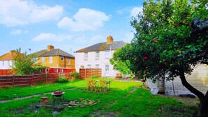 A residential backyard with a lawn, a small table and chairs, a tree with fruit, and a red fence. - Worcester Town Centre Home & Garden (Worcester)