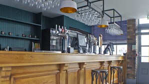 A bar area with a wooden counter, bar stools, and a wine rack with glasses. - OYO Tamworth Arms Boutique Pub & Hotel (Tamworth)