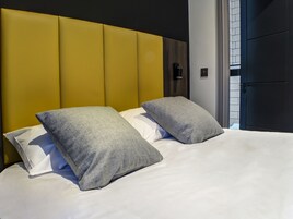 A bed with two pillows and a headboard in a hotel room.