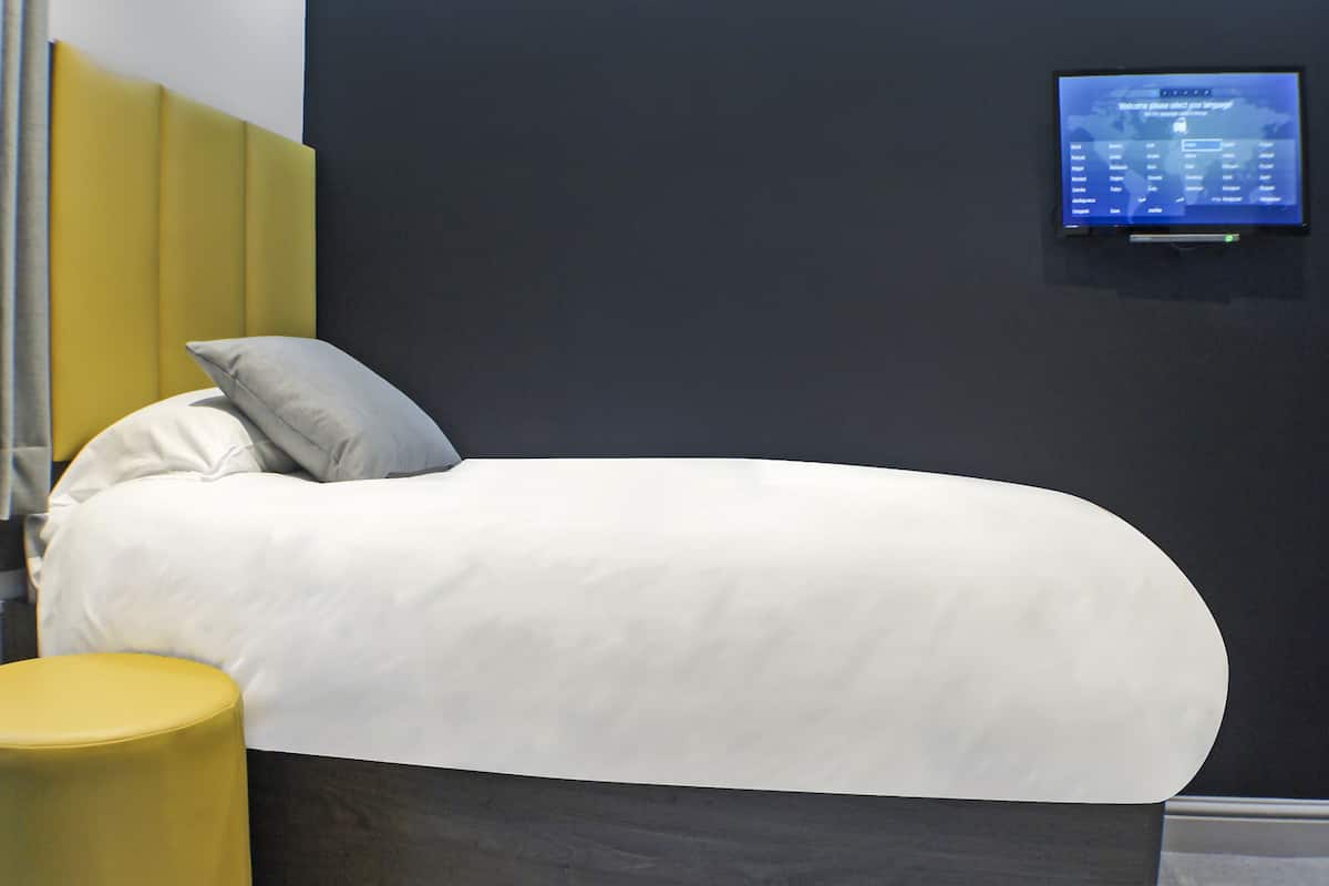 Ein modernes Hotelzimmer mit einem Bett, Kissen und einem digitalen Bildschirm, der eine Karte zeigt.