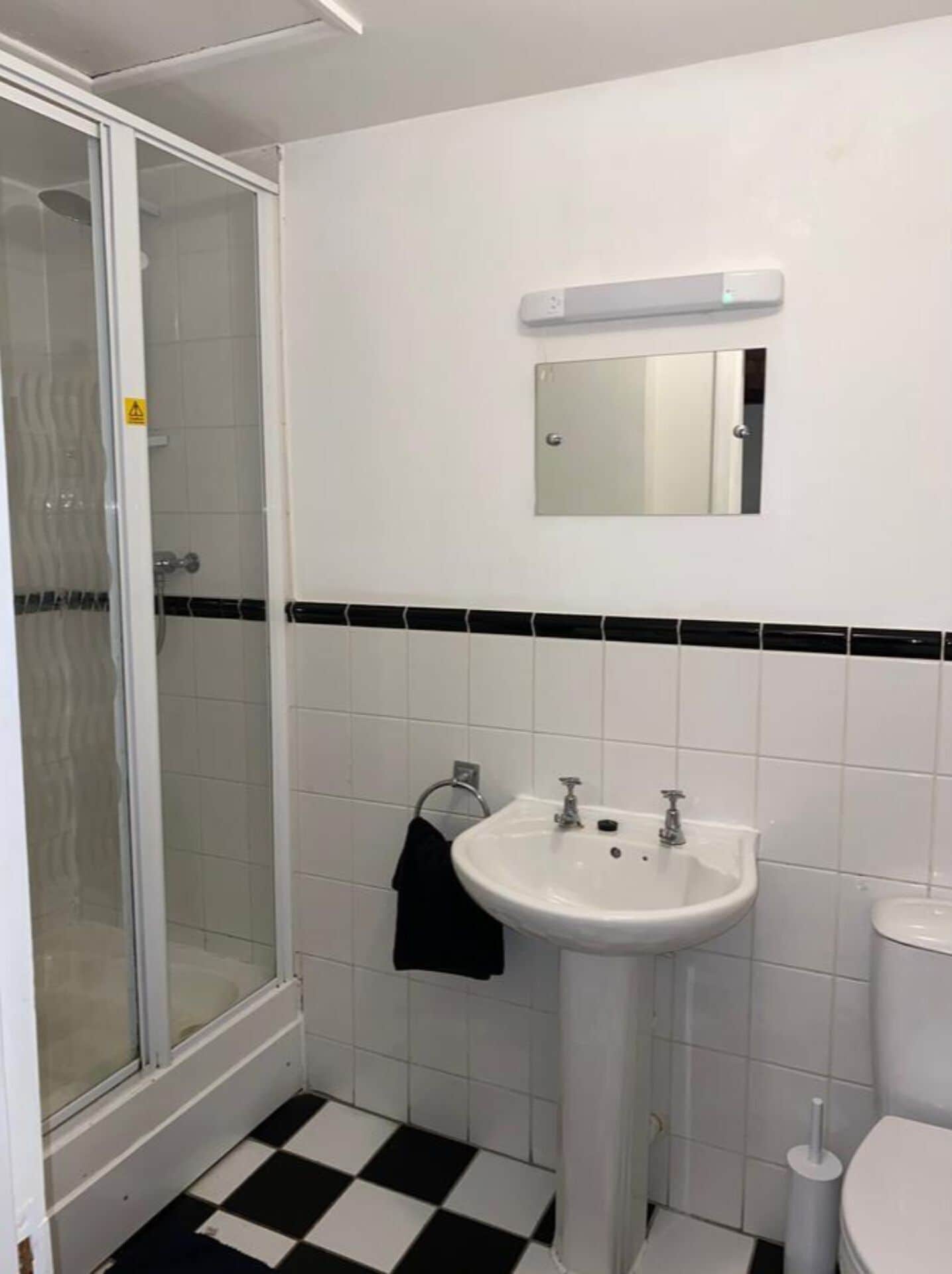 A bathroom with a white sink, a mirror, a toilet, and a shower.
