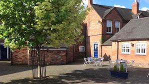 A courtyard with a brick building, a blue door, and outdoor seating. - OYO Tamworth Arms Boutique Pub & Hotel (Tamworth)