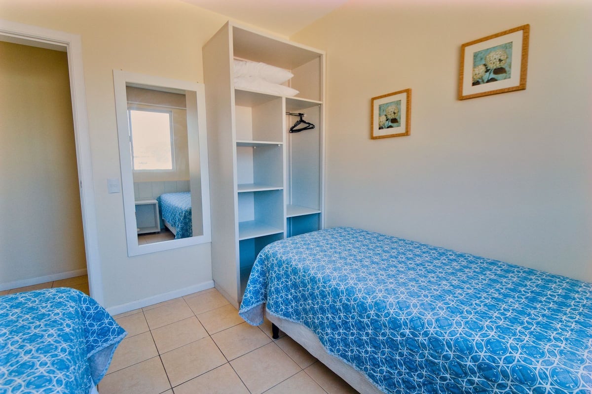 A bedroom with two beds, a wardrobe, and a window.