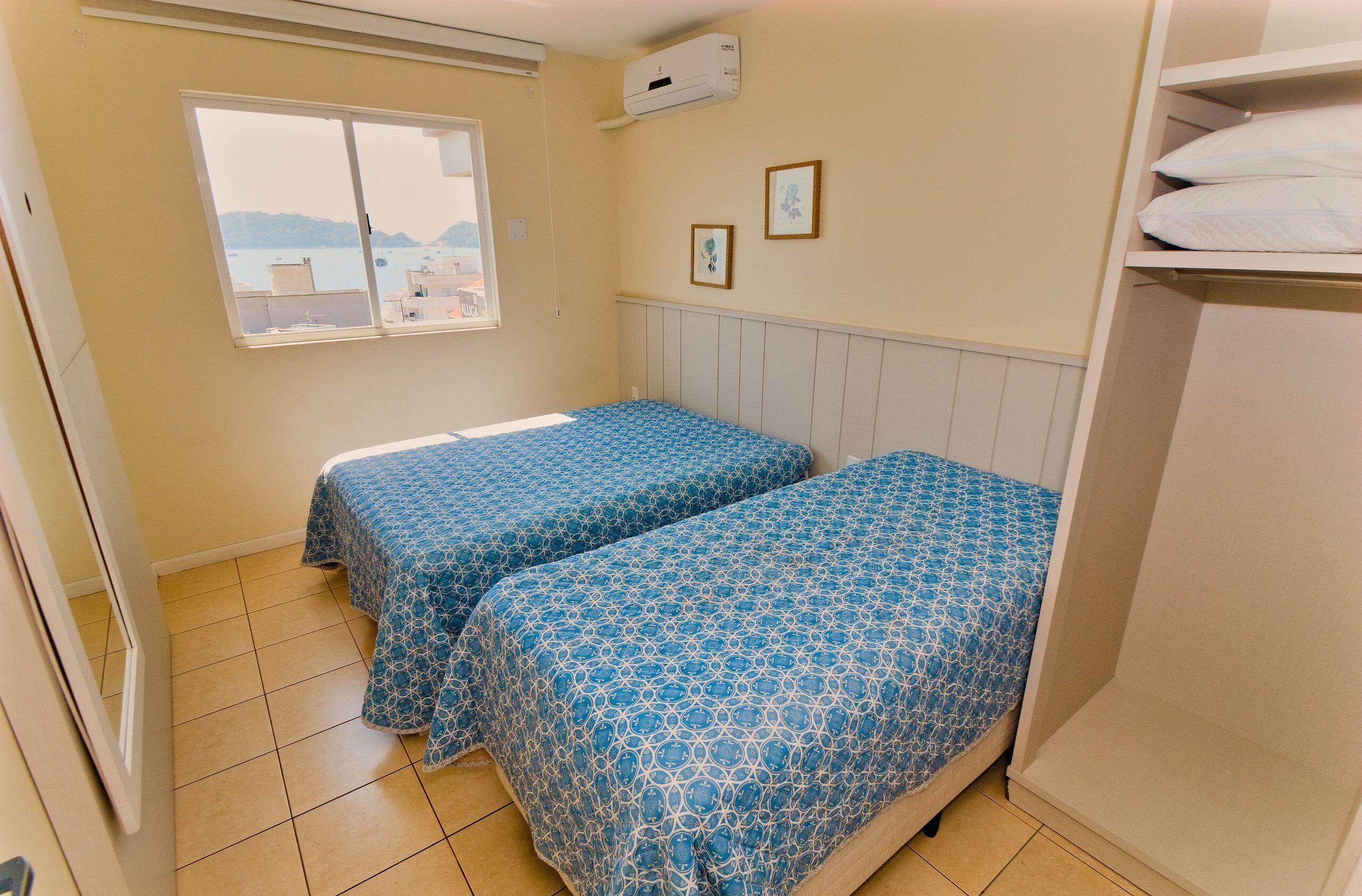 A bedroom with two beds, a window with a view, and a wardrobe.