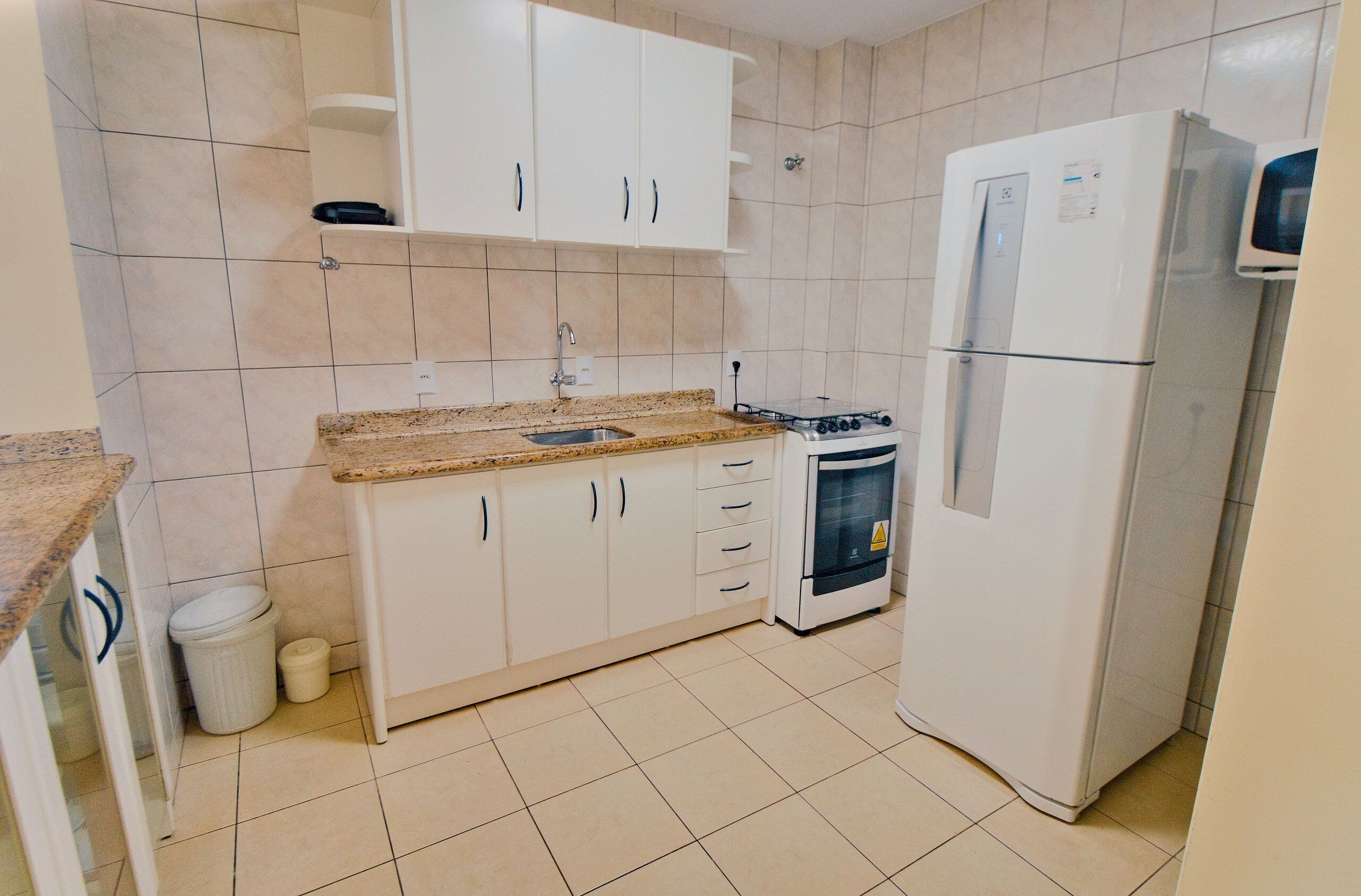 A kitchen with white cabinets, a granite countertop, a stove, and a refrigerator.