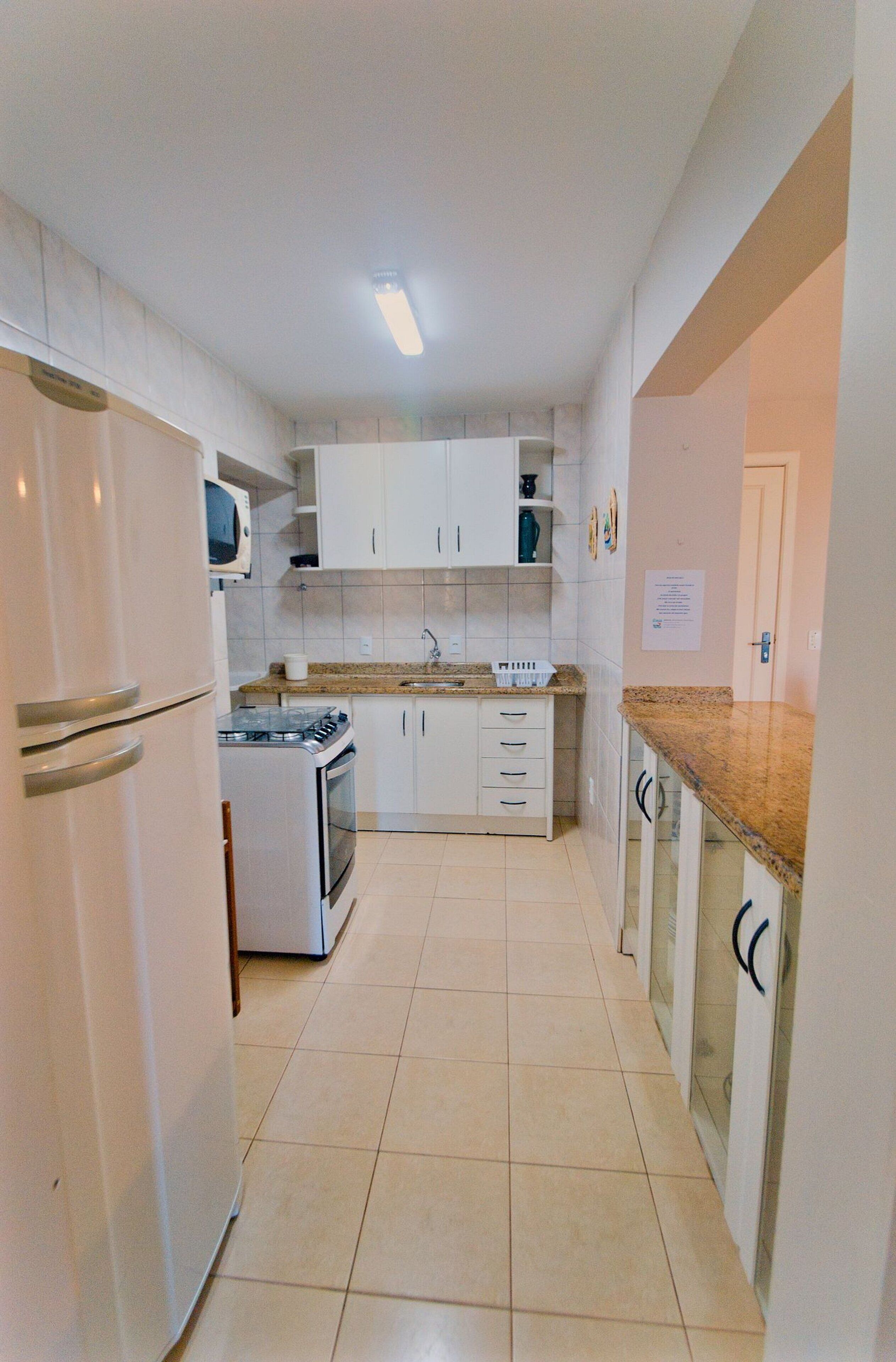 A compact kitchen with white cabinets, a stove, and a refrigerator.