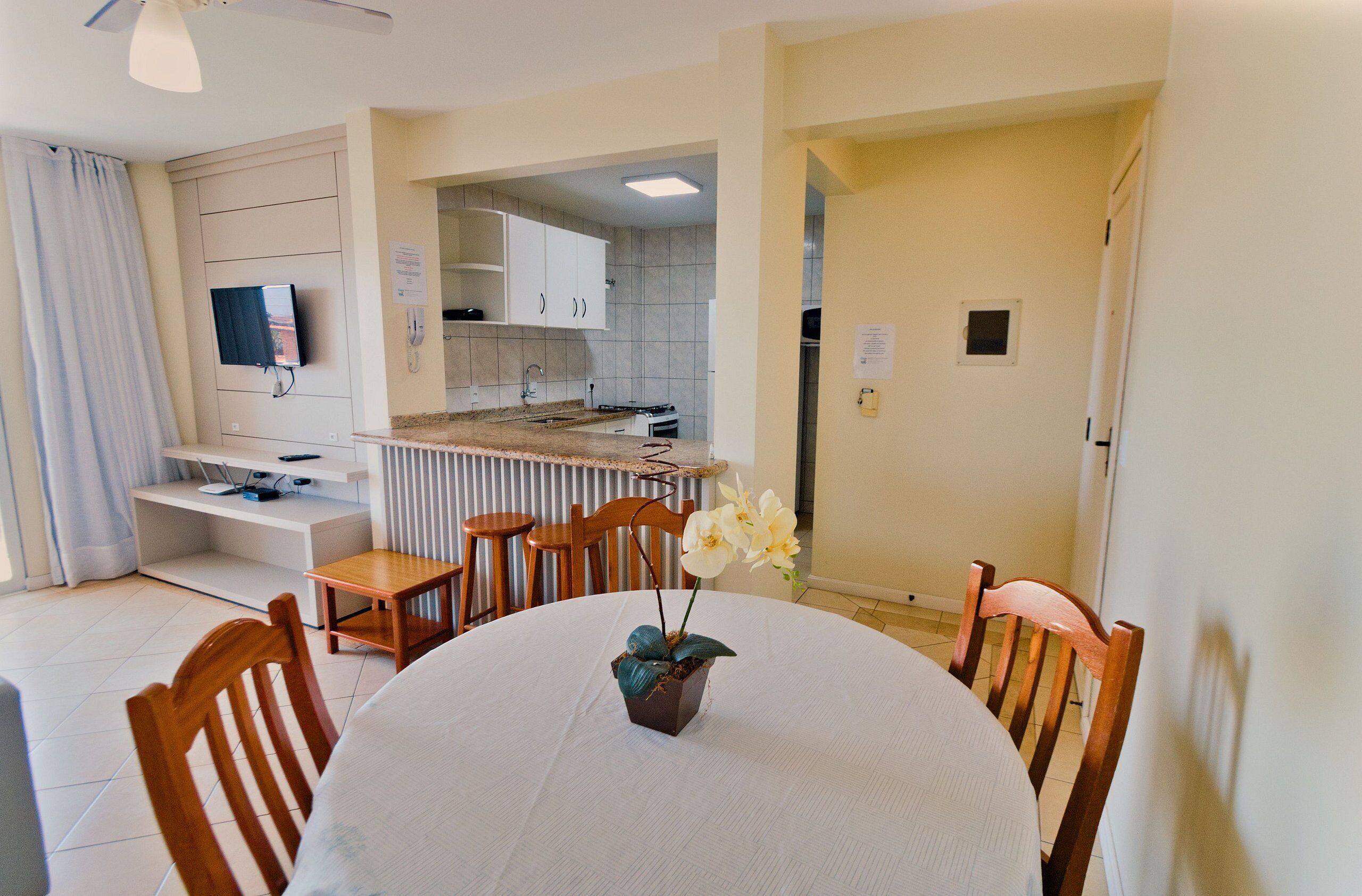 A dining area with a round table, chairs, and a flower centerpiece.