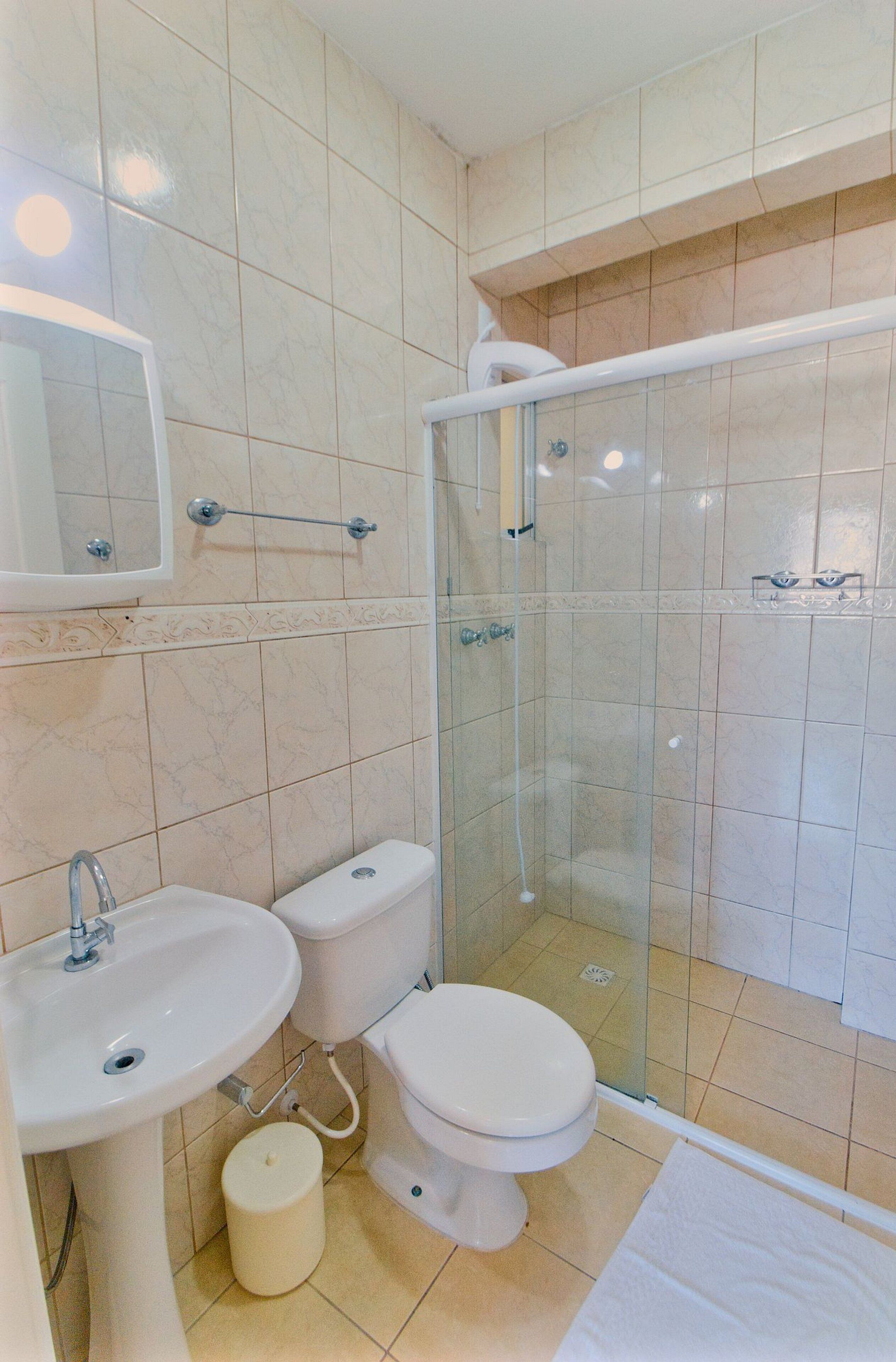 Un baño con lavamanos, inodoro y ducha con mampara de vidrio.