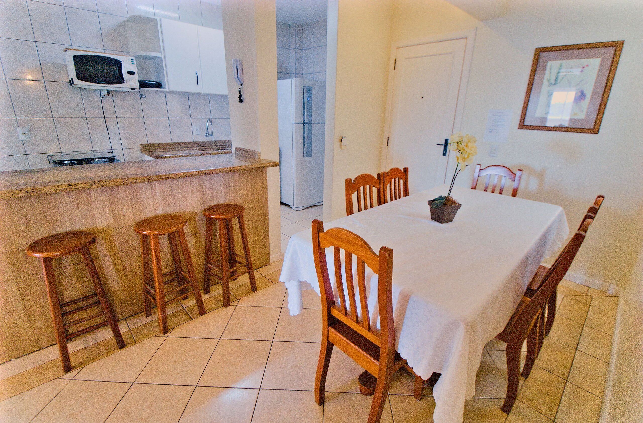 Una cocina compacta con microondas, refrigerador y taburetes de madera.