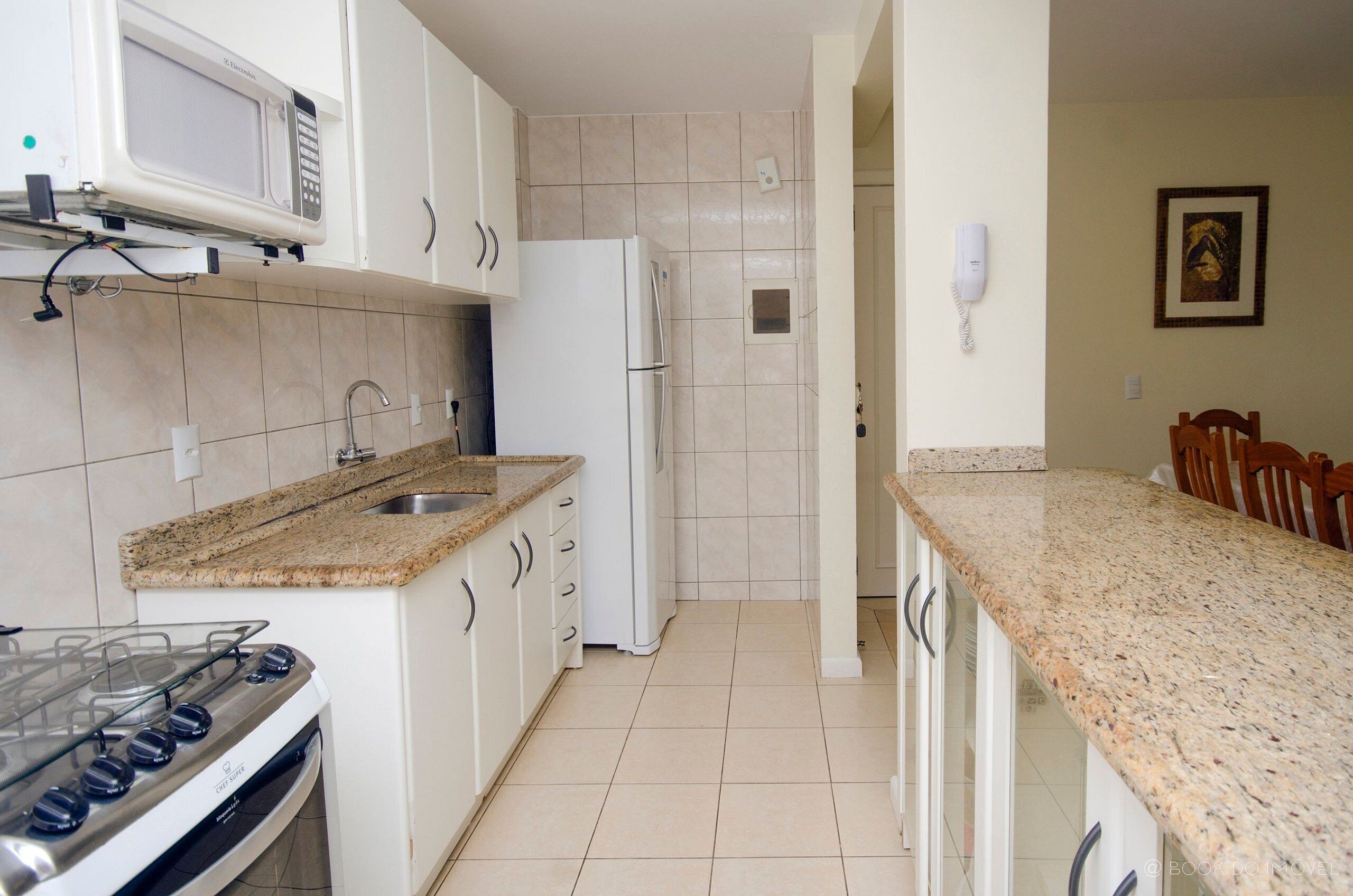 A kitchen with white cabinets, a granite countertop, a stove, a refrigerator, and a microwave.