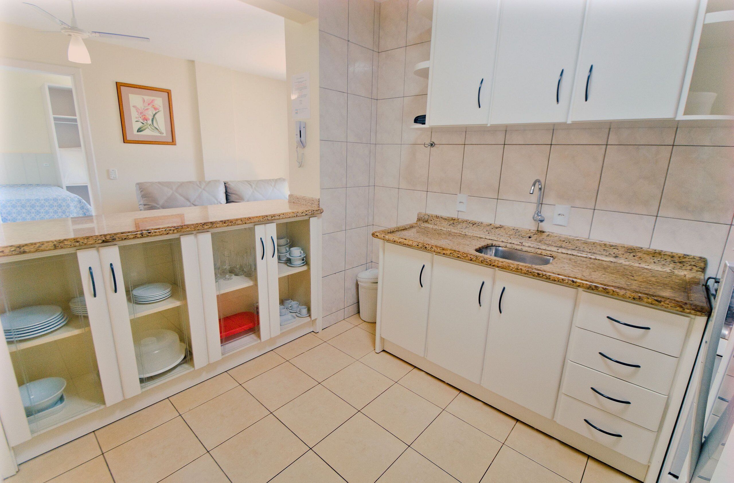 A compact kitchen with white cabinets, a granite countertop, and a sink.