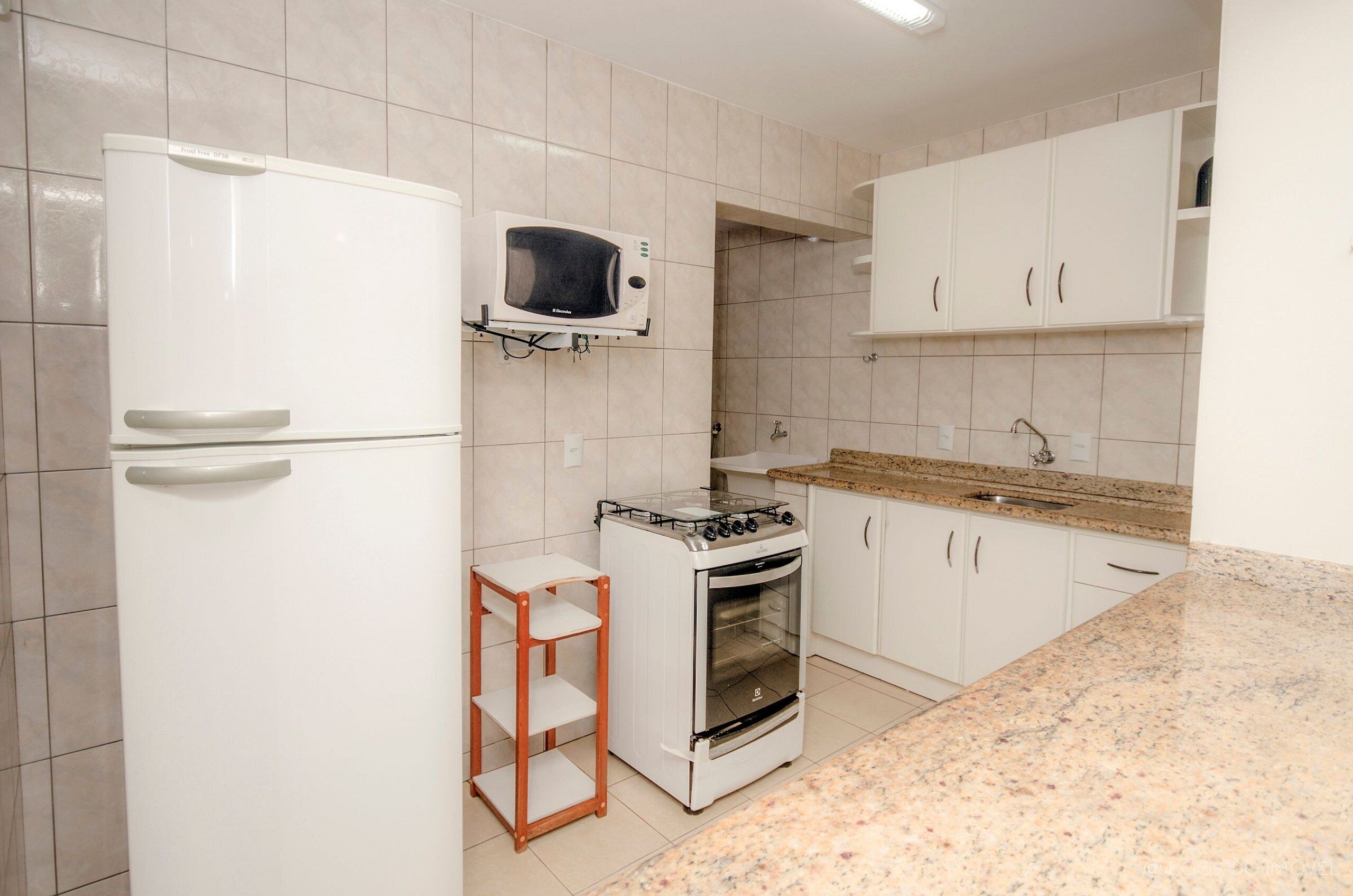 A kitchen with white cabinets, a microwave, a stove, and a granite countertop.