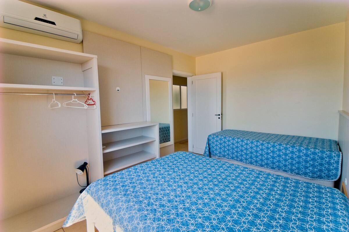 A bedroom with two beds, a wardrobe, and a mirror.