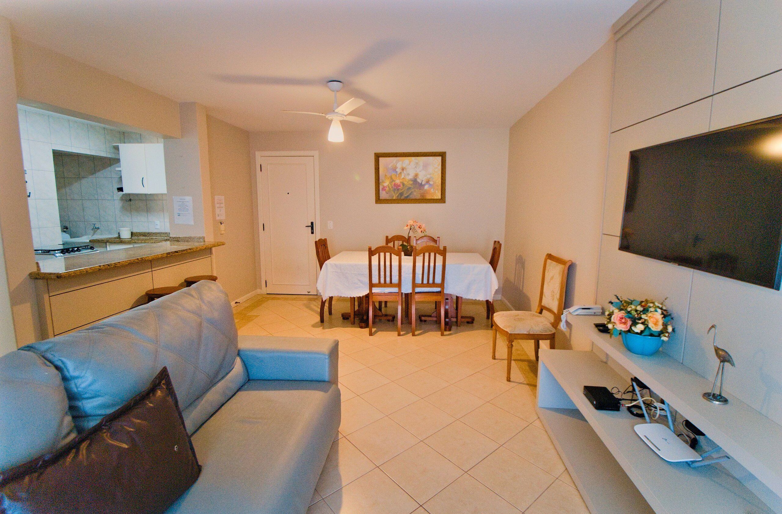 A compact living space with a dining table, a sofa, a TV, and a kitchen area.