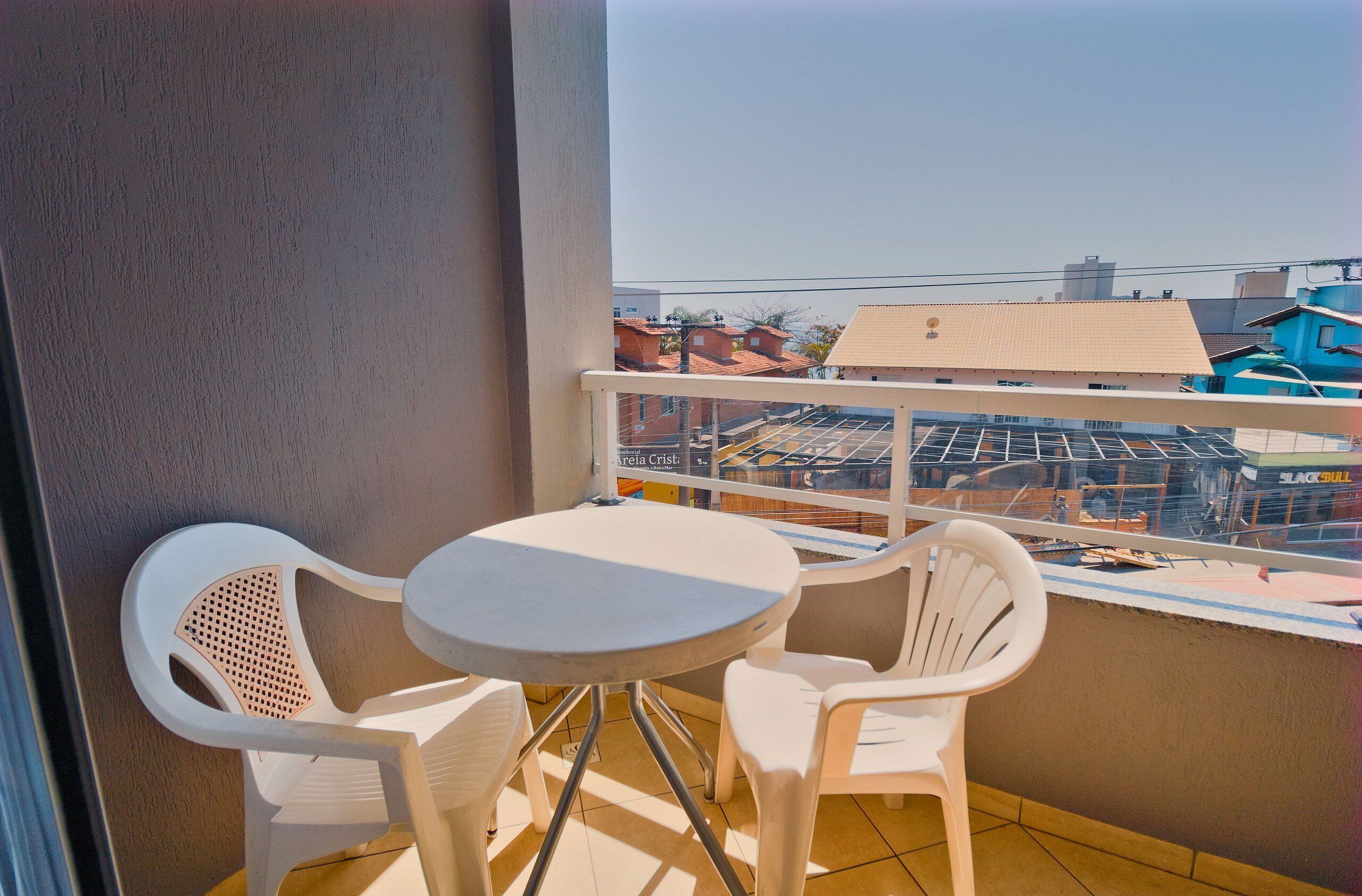 A balcony with a small round table and two white chairs.