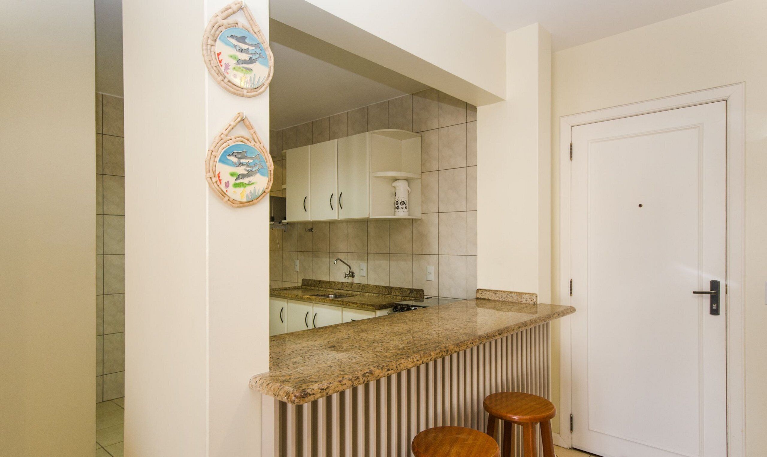 A kitchen with a granite countertop, white cabinets, and a white door.