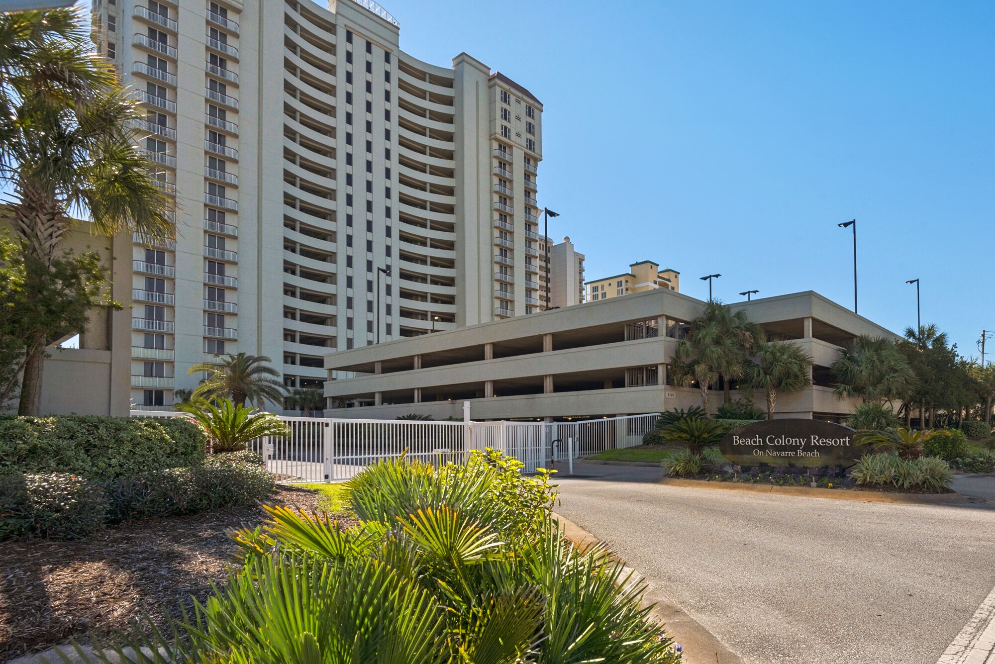 Een meerlaags parkeergarage naast een hotel, met een bord waarop staat 'Beach Colony Resort aan Navarro Beach'.