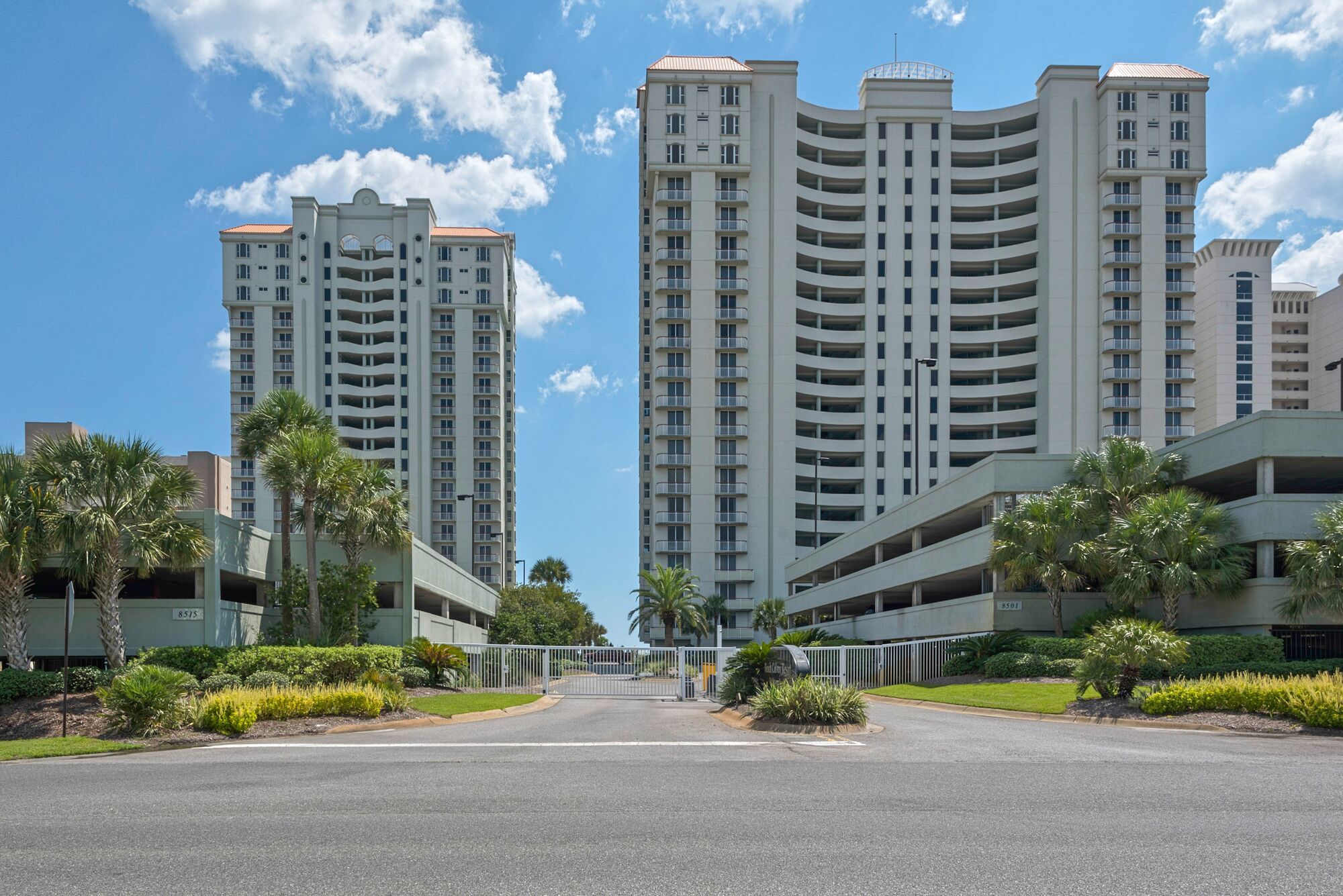A modern multi-story residential building with a curved facade, multiple balconies, and a parking garage.