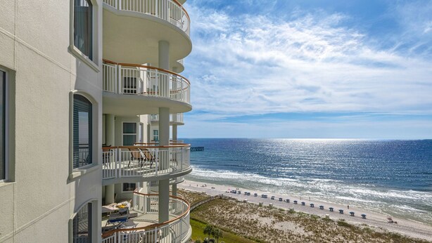 Un immeuble à plusieurs étages doté de balcons donnant sur une plage.
