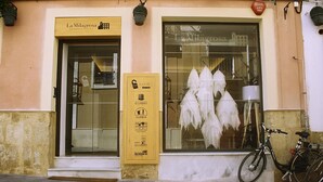 Ein Geschäftsvordach mit einem Schild für La Milagrosa Bed & Breakfast, ein Fahrrad vor der Tür und eine Schaufensterdekoration mit hängenden weißen Gegenständen.