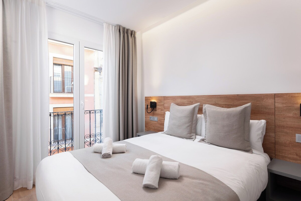 Une chambre d’hôtel avec un grand lit, une tête de lit en bois et une vue sur un balcon.