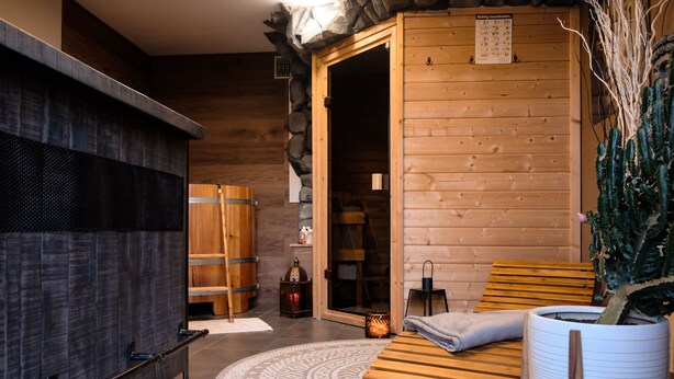 Una sala de sauna con bancos de madera, una toalla blanca y una planta en maceta.